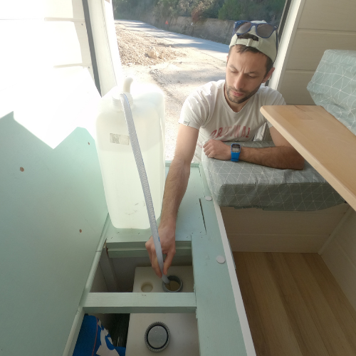 homme qui remplit cuve d'eau dans un fourgon